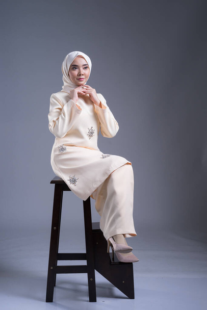 Kurung Pahang ve tesettüre bürünmüş güzel bir Müslüman kadın model. Gri giyinmiş Müslüman kadınlar için bir şehir yaşam tarzı. Güzellik ve tesettür moda konsepti. Tam boy portre - Fotoğraf, Görsel