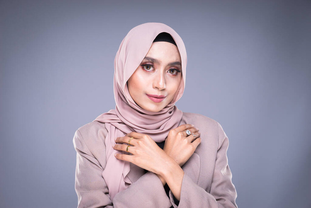 Фото красивой мусульманской модели в хиджабе и офисной одежде на сером фоне. Хиджаб и мусульманский стиль жизни
 - Фото, изображение
