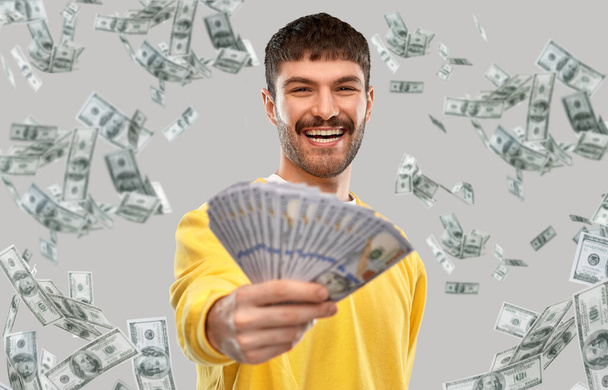 smiling young man in yellow sweatshirt with money - Foto, afbeelding