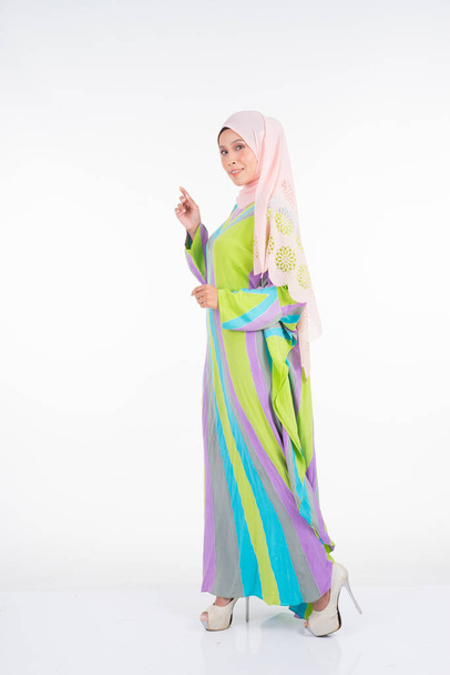 Beautiful female model wearing a pastel batik kaftan/caftan, a traditional dress for Muslim women isolated over white background. Stylish Muslim female hijab fashion lifestyle portraiture concept. - Photo, Image