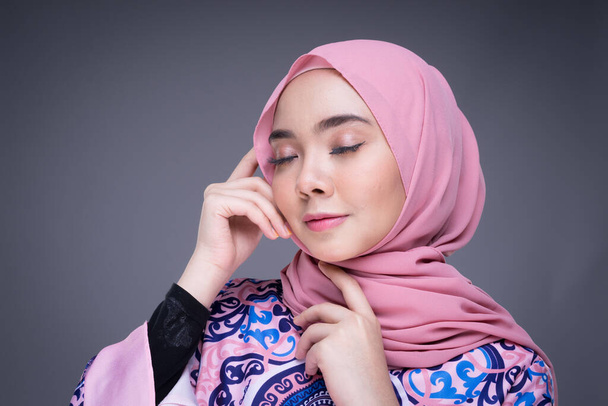 Magnifique mannequin musulmane portant des vêtements modernes avec hijab, un vêtement de style de vie urbain pour femmes musulmanes isolées sur fond gris. Concept de mode beauté et hijab. Portrait tête d'affiche. - Photo, image