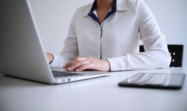 Ahşap masada dizüstü bilgisayar kullanarak çalışan bir adam. Klavyeye yazı yazan eller. - Fotoğraf, Görsel