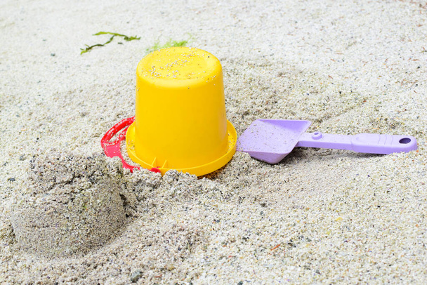 Gyerekjátékok a homokban. Vödör és ásó. Koncepció: nyaralás a tenger mellett gyermekekkel. - Fotó, kép