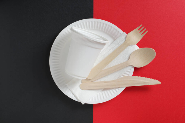 Papírový talíř, lžička, vidlička, nůž a sklo na dvoubarevném pozadí. Jednorázové stolní nádobí - Fotografie, Obrázek