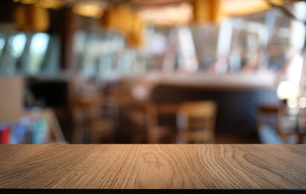 Mesa de madera vacía frente al fondo borroso abstracto de la cafetería. se puede utilizar para la exhibición o el montaje de sus productos.Mock para arriba para la exhibición del producto - Foto, imagen