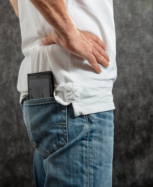 un teléfono inteligente está en el bolsillo trasero del hombre jean - Foto, imagen