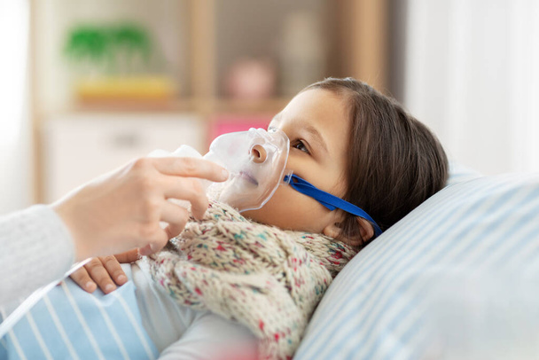 mother and sick daughter with oxygen mask in bed - Foto, Bild