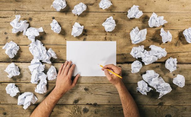 Yazmak için boş kâğıt kağıtları tutan eller mi yoksa buruşuk kağıt toplarıyla çevrili bir kalemle fikirler mi? Beyin Fırtınası Kavram resmi - Fotoğraf, Görsel