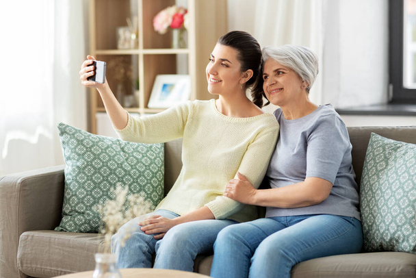 senior mother with daughter taking selfie at home - Foto, afbeelding