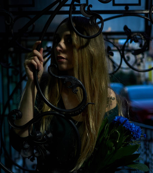 Girl with a bouquet of blue flowers in the evening on the street. - Fotografie, Obrázek