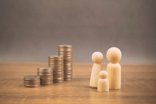 Многие монеты сложены в форме графика с семейной деревянной куклой для экономии денег идеи и страхования финансового планирования
. - Фото, изображение