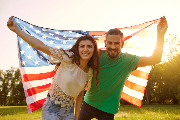 Couple with american flag celebrating america independence day standing in park. - Photo, image