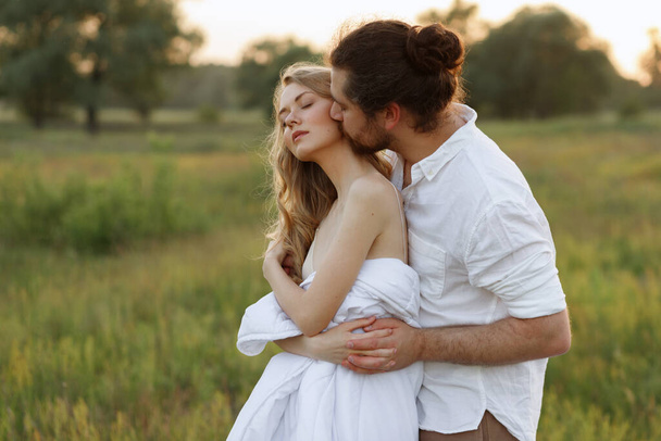 la pareja está enamorada y besándose en el campo en el verano. luz solar suave
. - Foto, imagen