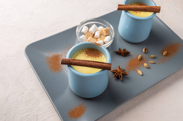 Two blue cups with traditional Indian masala chai tea with spices and sugar on a ceramic tray on a light background. Selective focus - Photo, Image