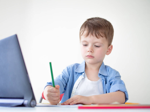 Online e-lessons για παιδιά προσχολικής ηλικίας. Παιδί που ψάχνει το μάθημα βίντεο σε μια ταμπλέτα στο σπίτι, μαθαίνοντας να σχεδιάζει - Φωτογραφία, εικόνα
