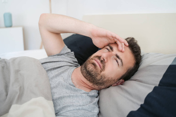 Rusteloze man die vroeg wakker wordt met hoofdpijn na een zware nacht - Foto, afbeelding