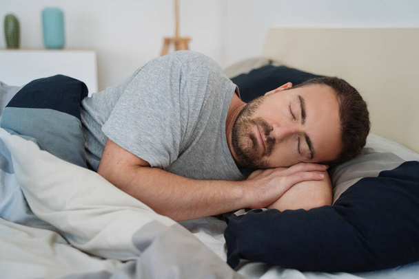 Мужской портрет спящего в постели чувствует себя комфортно
 - Фото, изображение