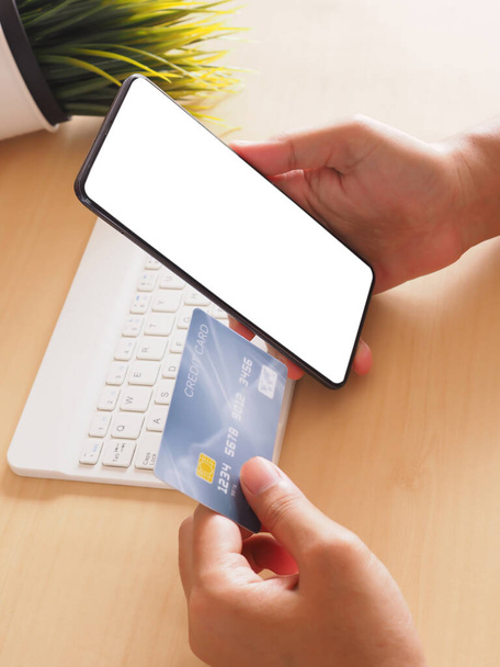Frau hält Smartphone mit leerem Bildschirm und Kreditkartenattrappe am Schreibtisch, Konzept Finanztransaktion - Foto, Bild