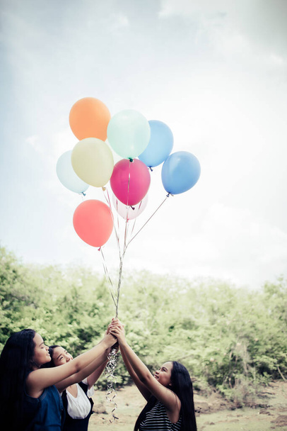 Happy group girl friends hand holding multicolored balloons - Photo, Image