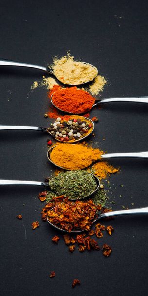 spices on a metal spoon on a black background - Fotoğraf, Görsel