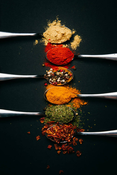 spices on a metal spoon on a black background - Foto, Bild