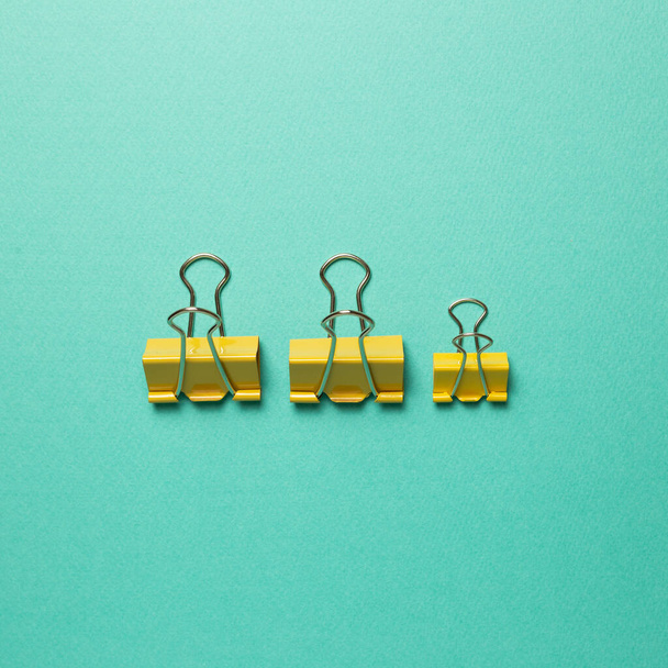 Yellow metal binder clips on mint green background. top view - Photo, Image