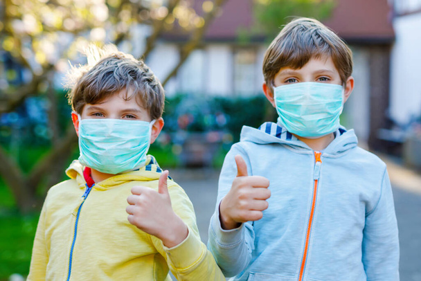 Dva chlapci v lékařské masce jako ochrana proti pandemické koronavirové chorobě. Děti, milí sourozenci a nejlepší přátelé používající ochranné prostředky jako boj proti covidu 19. - Fotografie, Obrázek