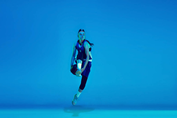 Young caucasian female basketball player isolated on blue studio background in neon light - Foto, immagini