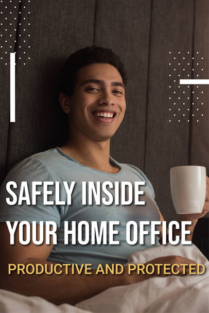 smiling mixed race man holding cup of coffee near safely inside your home office, productive and protected lettering in bedroom  - Photo, Image