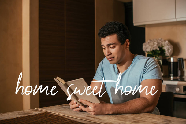 handsome mixed race man reading book near home sweet home lettering  - Fotoğraf, Görsel