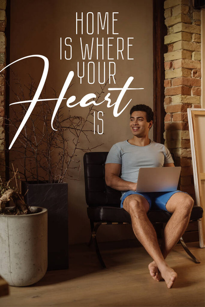 happy mixed race freelancer chilling with laptop near lettering home é onde seu coração está lettering
  - Foto, Imagem