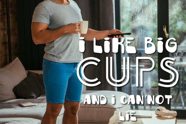 bijgesneden weergave van de mens met kopje koffie houden afstandsbediening in de buurt ik hou van grote koppen en ik kan niet liegen belettering  - Foto, afbeelding