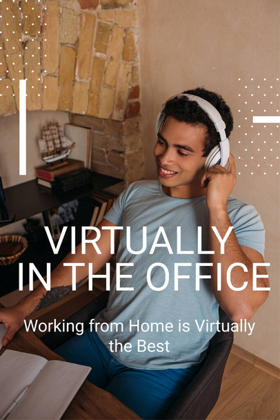 homem de raça mista sorrindo tocando fones de ouvido perto virtualmente no escritório, trabalhar em casa é virtualmente a melhor letra
  - Foto, Imagem