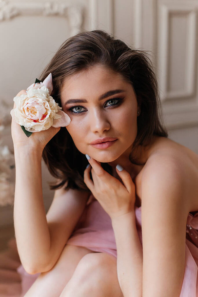 photo in the style of advertising expensive perfumes. close-up portrait of a girl with big eyes and a fresh peony flower in her face - Zdjęcie, obraz