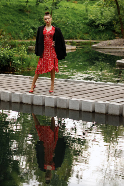 дівчина в червоній сукні на прогулянці в міському парку влітку. одяг на побачення
 - Фото, зображення