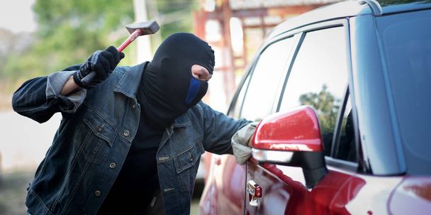 Ladrón de coches con un martillo y vidrios rotos
 - Foto, imagen