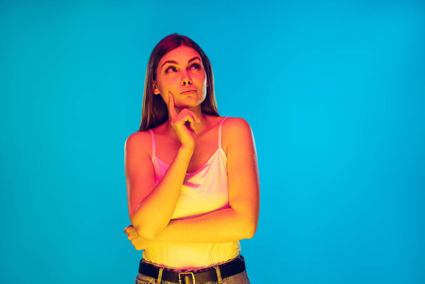 Caucasian young womans portrait isolated on blue background in neon light - Fotó, kép