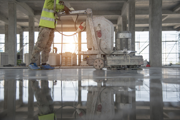 Robotnik budowlany produkuje zaprawę i wykończenie betonu mokrego specjalnym narzędziem. Pływające ostrza. Do wygładzania i polerowania betonu, betonu podłogowego - Zdjęcie, obraz