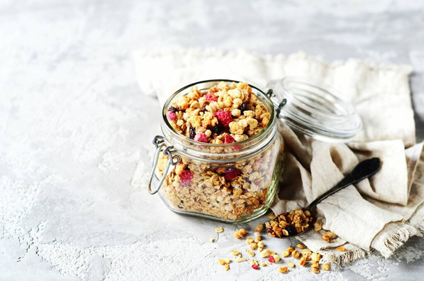 Homemade granola with berries and nuts in a glass jar on a gray background - Photo, Image