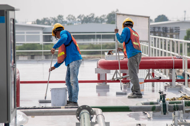 Строители покрывают эпоксидную краску на крыше плиты для водонепроницаемой защиты
 - Фото, изображение