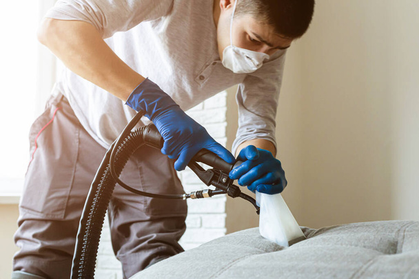 Man cleaning sofa chemical cleaning with professionally extraction method. Upholstered furniture. Early spring cleaning or regular clean up. - Foto, Imagem