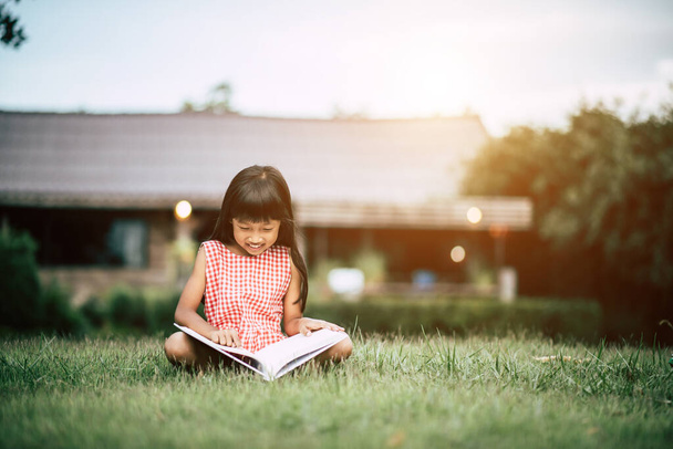 Petite fille lisant un livre dans le jardin de la maison - Photo, image