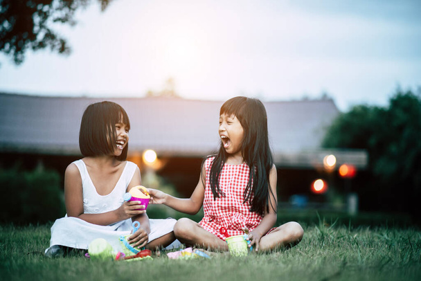 Twee kleine meisje spelen speelgoed in huis tuin - Foto, afbeelding