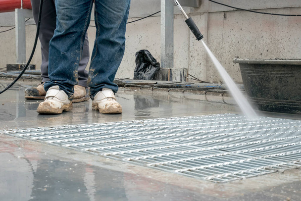 Bouwvakker betonnen vloer reinigen met hoge druk waterstraal - Foto, afbeelding
