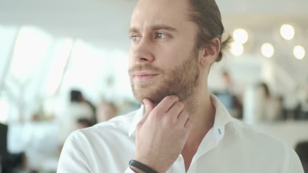 A close-up view of a handsome young businessman is looking to the side in a city cafe indoors - Felvétel, videó