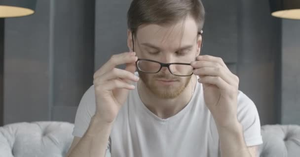 Close-up portrait of tired Caucasian man taking off eyeglasses and rubbing temples. Handsome exhausted brunette guy having stress. Headache, tension pain, overworking. Cinema 4k ProRes HQ. - 映像、動画