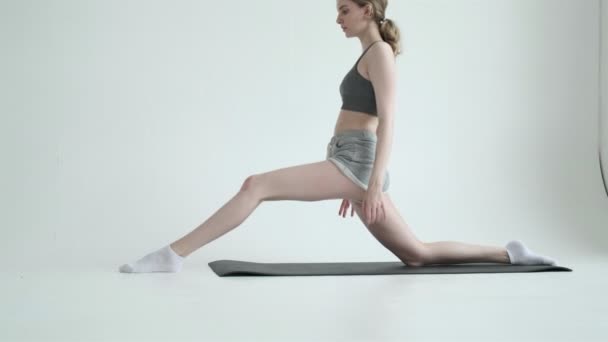 Jong fit meisje doet splits oefening in een heldere kamer. Pilates, fitnesstraining - Video