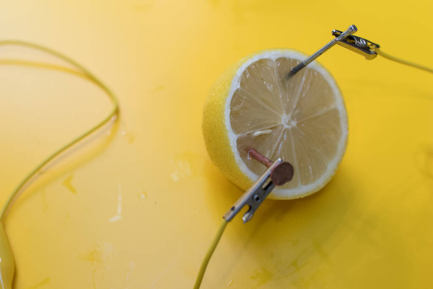Citrónová baterie STEM aktivita s citrony, krokodýlími svorkami, zinkem a měděnými hřebíky. Přirozená baterie zapnout vedl. vědecký experiment pro děti na elektřině na žlutém pozadí - Fotografie, Obrázek