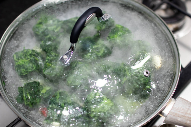 Frozen chicory cubes are cooked in a pan on the fire of a domestic kitchen. Preparation of frozen vegetables in cubes with smoke and water vapor from thawing - Photo, Image