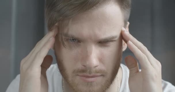Face of stressed Caucasian brunette man rubbing temples in slow motion. Close-up portrait of anxious young guy having migraine and headache. Tension, stress, anxiety. Cinema 4k ProRes HQ. - Video, Çekim